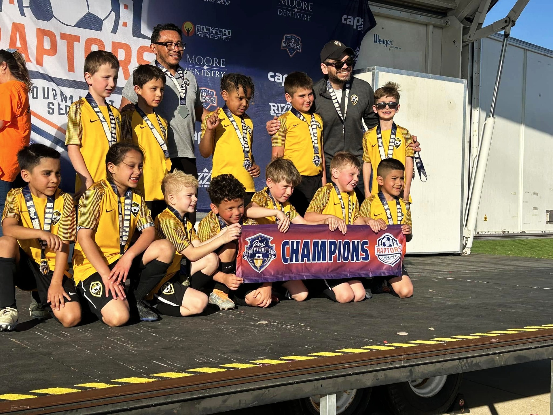 ACE Boys team in yellow kits with Champions banner at Raptors Cup